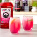 A glass of pink Lotus Plant Power Skinny Energy Drink with a lemon slice.