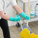 A man wearing green Ansell AlphaTec Solvex gloves is cleaning the floor with a mop.