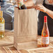 A hand pouring wine into a brown ChoiceHD bag with a black handle.