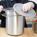 A woman in a chef's uniform using a Vollrath stainless steel double boiler set.