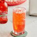 A close-up of a glass of red liquid with ice.