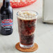 A close up of a glass of IBC Diet Root Beer with foamy bubbles next to a bottle of IBC Diet Root Beer.