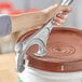 A person using a Choice aluminum pail opener to open a bucket.