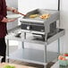 A man cooking food on a Vollrath countertop griddle.