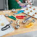 A woman using a blue EZ grip scoop to scoop cookie dough into a metal bowl.