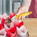 A person's hand using a yellow Choice #20 Thumb Press Disher to scoop yellow ice cream.