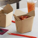 Two Emperor's Select Kraft Microwavable paper take-out containers with food inside on a table in an Asian cuisine restaurant.