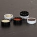 A set of black and white straight-sided melamine ramekins, each holding different sauces or seasonings.