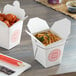 Two Emperor's Select Asian take-out containers with noodles and meatballs.