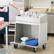 A man standing next to a ServIt flatware cart with utensils on it.