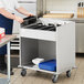 A woman putting flatware trays into a stainless steel ServIt cart.