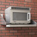 A stainless steel microwave shelf with a microwave on it.