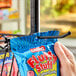 A person holding a blue bag of candy using a Regency black epoxy ledge hook.