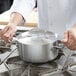 A chef using a Vollrath Miramar casserole pan on a stove.