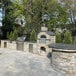 A Chicago Brick Oven hybrid wood and natural gas-fired pizza oven kit with a stone arch over the oven and a patio.