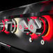 A close up of a black and red Crown Verity liquid propane grill with red knobs.
