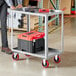 A man standing next to a Lavex steel utility cart with two trays on it.