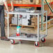 A man standing next to a Lavex utility cart with wheels.