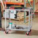 A man standing next to a Lavex steel utility cart with two trays.