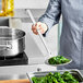 A chef uses a Vollrath Jacob's Pride wire mesh skimmer to remove broccoli from a bowl.