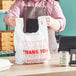 A man holding a white plastic bag with red "Thank You" text.