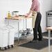 A man standing at a Regency wood top work table in a professional kitchen.