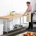 A man in an apron stands next to a Regency wood top work table.