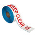 A roll of white tape with red text that reads "Emergency Exit Keep Clear"