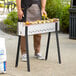 A man wearing an apron cooking on a Backyard Pro stainless steel kebab grill outside.