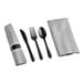 A close-up of a Hoffmaster CaterWrap napkin and black plastic cutlery set with a fork, knife, and spoon.