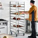 A heavy-duty aluminum bun and sheet pan rack with 12 end load slots, shown holding trays of baked goods in a commercial kitchen.