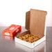 A white customizable pie box with cookies inside on a table.