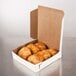 A white customizable pie box filled with pastries on a table.