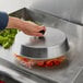 A person holding a Choice aluminum basting cover over a pan of vegetables.