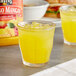 A glass of Langers mango juice with ice on a table.