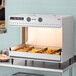 A Hatco freestanding multi-product warming station with food in a tray on a counter.