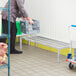 A man pushing a cart with a Regency dunnage rack in a grocery store aisle.