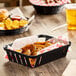 A Carlisle black munchie basket filled with food on a table.