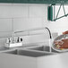 A person using a 1.8 GPM deck-mount faucet with a 12" swing spout to wash dishes in a sink.