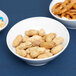 A white bowl of peanuts and pretzels.