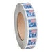 A roll of white tape with blue and red stickers with "Point Plus 1" x 1" Product of USA Permanent Label" on it.