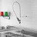 A stainless steel sink with a Regency pre-rinse faucet and hose on a counter.
