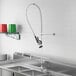 A Regency pre-rinse faucet with a double-jointed add-on faucet above a stainless steel sink.