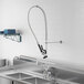 A Regency pre-rinse faucet and double-jointed faucet mounted on a stainless steel sink.