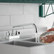 A person washing a plate in a sink using a 1.8 GPM deck-mount faucet.