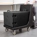 A man using a black Cambro tray carrier on wheels.