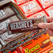 A person's hand holding a HERSHEY'S King Size Milk Chocolate Bar.