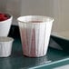 A white tray holding Genpak white paper souffle cups filled with a drink.