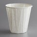 A white Genpak paper souffle cup on a gray surface.