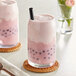 A pink drink in a glass with a straw and a straw on top.